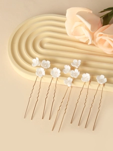 Detail of white ceramic flower hair pins with crystals and gold wavy U-shaped clips
