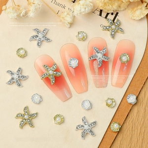 Detail of starfish and shell nail charms with pearls and rhinestones on orange nails