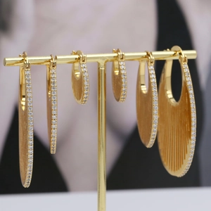 Dettaglio di tre paia di orecchini a cerchio ovali in ottone placcato oro 18k e zirconi