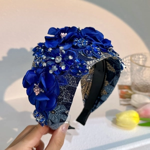 Detailed close-up of dark blue lace headband with fabric flowers and sparkling rhinestones