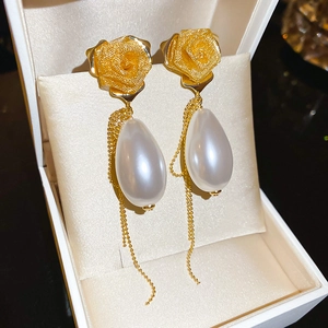 Detail of rose stud earrings with white teardrop pearls and elegant gold tassels