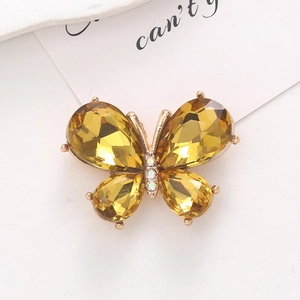 Macro di ciondolo a farfalla dorata con strass gialli su un biglietto dallo stile minimal