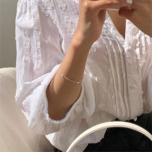 Close-up of minimalist S925 silver olive bead bracelet worn on a woman's wrist