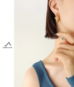 Gros plan de boucles d'oreilles dorées martelées en U avec perle sur mannequin