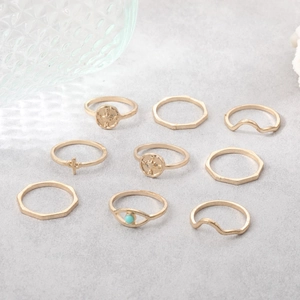 Detail of 9-piece gold ring set featuring waves, crosses, and turquoise stones