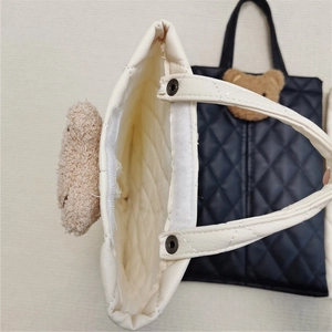 Detail of quilted leather tissue holder with velcro closure and plush bear embroidery