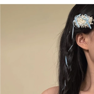Détail de la pince à cheveux en perles avec rubans en velours bleu clair sur cheveux