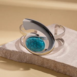 Detail of silver wide cuff bracelet featuring an oval blue turquoise stone on stone tray