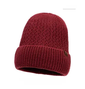 Detail view of red knitted beanie with thick textured pattern and leather patch