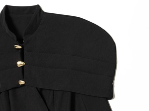 Detail of tailored black blazer featuring a luxury gold teardrop metal button closure