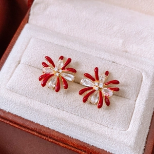 Macro shot of 18k gold flower earrings with red enamel and zircon in a gift box