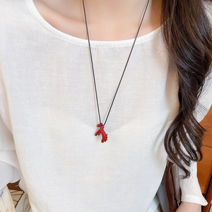Close-up of red horse pendant necklace with black cord on a model neck