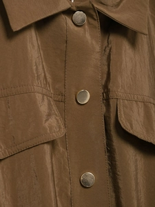 Détails des boutons en métal doré et poche à rabat sur cette chemise en satin marron