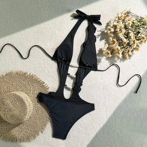 Close-up of black cutout swimsuit featuring elegant pearl buckles and ruffle edge detail