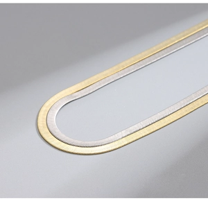 Dettaglio ravvicinato di catene a serpente piatte color oro e argento lucido