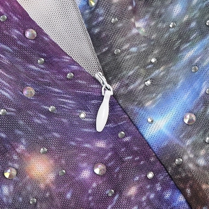 Détail du tissu à imprimé galaxie avec strass et fermeture éclair invisible blanche