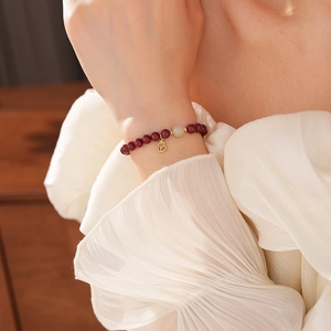Close-up of cinnabar bead bracelet with a gold gourd pendant featuring the Fu character