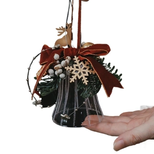 Christmas glass bell ornament with red velvet bow and pine needles on white background