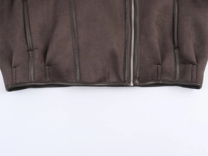 Detail of dark brown suede jacket showing leather trim and silver metal zipper closure