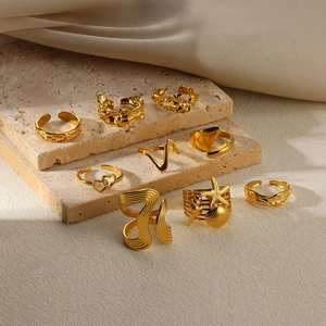Set of eight gold adjustable open rings displayed on a minimalist travertine stone background