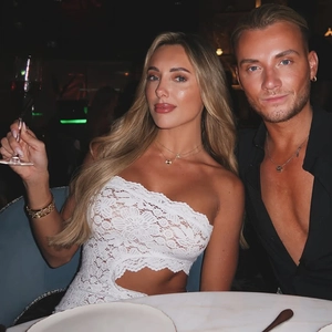 Dettaglio di un abito bianco in pizzo monospalla con elegante apertura in vita e ricamo floreale