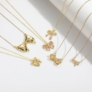 Six assorted gold bow pendant necklaces with zircon and gemstones on a white background