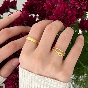 Macro shot of 925 sterling silver matte gold rings set against dark red flowers