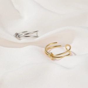 Detailed shot of double twisted gold and silver stainless steel rings on white silk