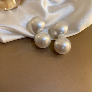 Macro shot of large round white pearls on elegant silk fabric showing high-gloss texture