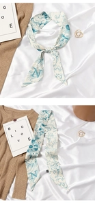 Close-up of a silk twilly scarf with blue wave patterns and a bold letter N print