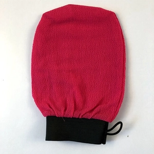 Close-up of red exfoliating scrub glove with granular texture and black elastic wristband
