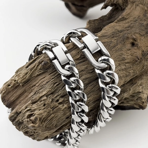 Close-up of thick silver Cuban link bracelet with heavy clasp on weathered wood