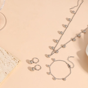 Macro shot of silver stainless steel bead necklace and bracelet set on a stone display