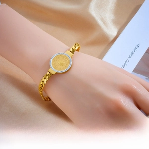 Detail eines Goldmünzen-Armbandes mit funkelndem Mittelstein und robuster Panzerkette