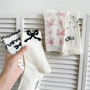 Detail of white cotton socks with cute black bow decoration and varied patterns