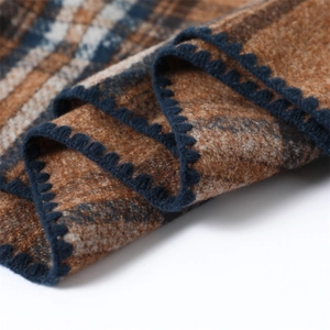 Detailed view of plaid cashmere feel scarf with dark blue scalloped edge and thick texture