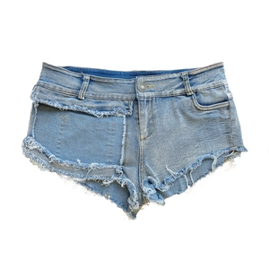 Dettaglio di pantaloncini in denim azzurro con bordi sfrangiati e tasche irregolari