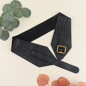 Detail of black crocodile texture belt with gold metal buckle on minimalist background