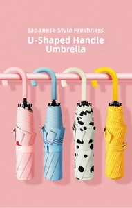 Detailed view of foldable sun umbrellas with ergonomic U-shaped handles in varied colors