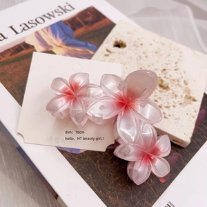 Detail showing a 10cm gradient pink plumeria flower hair claw clip on stone background