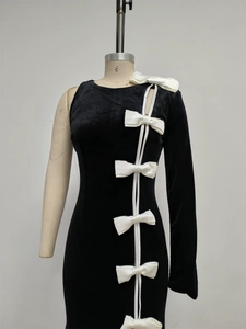 Detail of white satin bows on asymmetric black velvet evening dress with slim fit