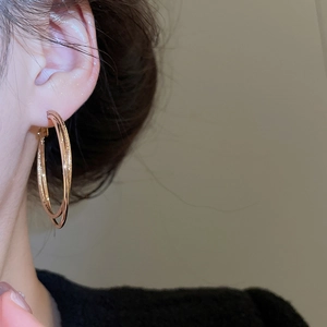 Detail of elegant double-layered rose gold hoop earrings worn on a model in a warm setting