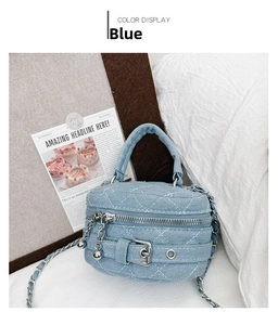 Detail of blue denim barrel bag with quilted stitching, chain strap and top handle