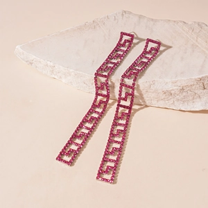 Detailed close-up of long tassel earrings with pink rhinestones and Greek Key pattern
