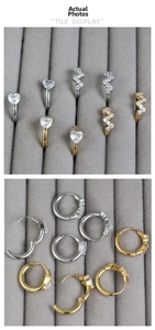Détail de boucles d'oreilles huggies en or et argent avec motifs cœur et éclair en zircone