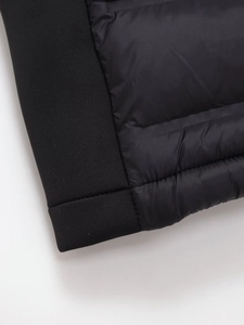 Détail du gilet matelassé noir montrant la texture de couture et l'ourlet côtelé