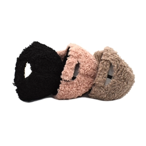 Detailed close-up of warm faux lamb wool ear muffs in black, pink, and beige colors