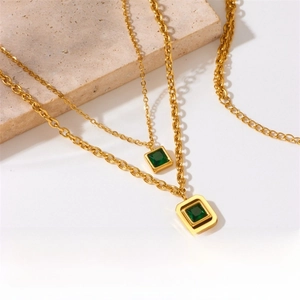 Detail of gold-plated stainless steel chain with a green square gemstone pendant