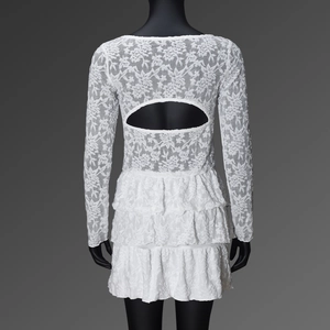 Detail of white lace dress featuring a three-tier cake skirt and backless cutout design