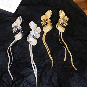 Élégantes boucles d'oreilles fleuries dorées et argentées avec glands sur fond noir